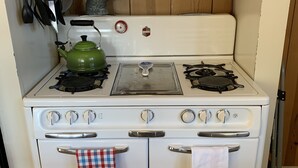 A white stove with four burners and a range hood above it. - Family and pet friendly close to beaches. SC Rental Permit 241396 (Santa Cruz)