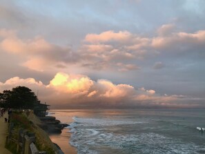 A coastal scene with a sandy beach, waves, and a cloudy sky.