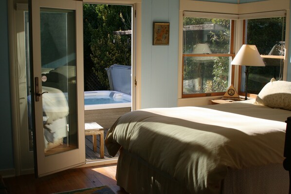 A bedroom with a bed, a window, a lamp, and a door leading to a balcony.
