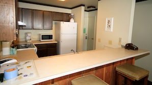 A kitchen with wooden cabinets, a white refrigerator, a microwave, and a coffee maker. - Mammoth Ski & Racquet Club #78 (Mammoth Lakes)