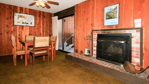A room with wooden walls, a fireplace, a dining table with chairs, and a ceiling fan. - Mammoth Ski & Racquet Club #78 (Mammoth Lakes)