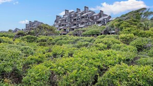 A multi-story building with a stone facade and multiple chimneys, surrounded by dense green vegetation. - Windswept 4463! Oceanfront 3 BR Condo, Great Location! (Kiawah Island)