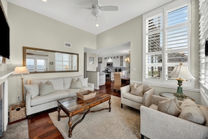 A spacious living room with a sofa, armchairs, a coffee table, and a dining area with a kitchen in the background.