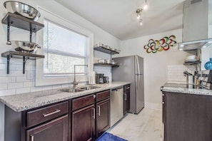 Una cucina moderna con piani di lavoro in granito, elettrodomestici in acciaio inossidabile e pensili in legno scuro.