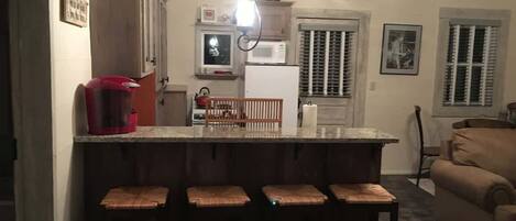 Une cuisine équipée d’un coin bar avec des tabourets, d’un four à micro-ondes et d’un réfrigérateur.