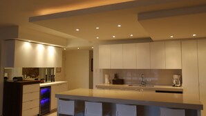 A modern kitchen with a central island, bar stools, and recessed ceiling lighting. -  Beautiful beachfront villa at the Wyndham Grand R Mar Rainforest Beach Resort  (Rio Grande)