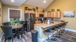 Een moderne keuken met een centraal eiland, barkrukken en een eethoek met een tafel en stoelen.