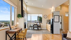 Amplia sala de estar con mesa de comedor, cocina y grandes ventanales con vistas.