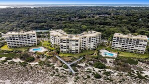 Vista aérea de un resort con varias edificaciones, un puente y una playa.