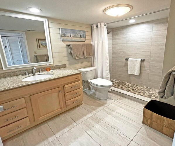 Un baño moderno con tocador de madera, inodoro y zona de ducha.
