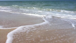 Una playa con cielos despejados y olas suaves.