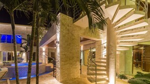 A modern hotel with a pool, palm trees, and a spiral staircase. - Bachelor Mansion Punta Cana - 24 GUEST - Luxury 9BR Villa Coral GATED Community (Bavaro)