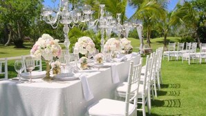 A table set for a wedding reception with white chairs and floral centerpieces. - Bachelor Mansion Punta Cana - 24 GUEST - Luxury 9BR Villa Coral GATED Community (Bavaro)