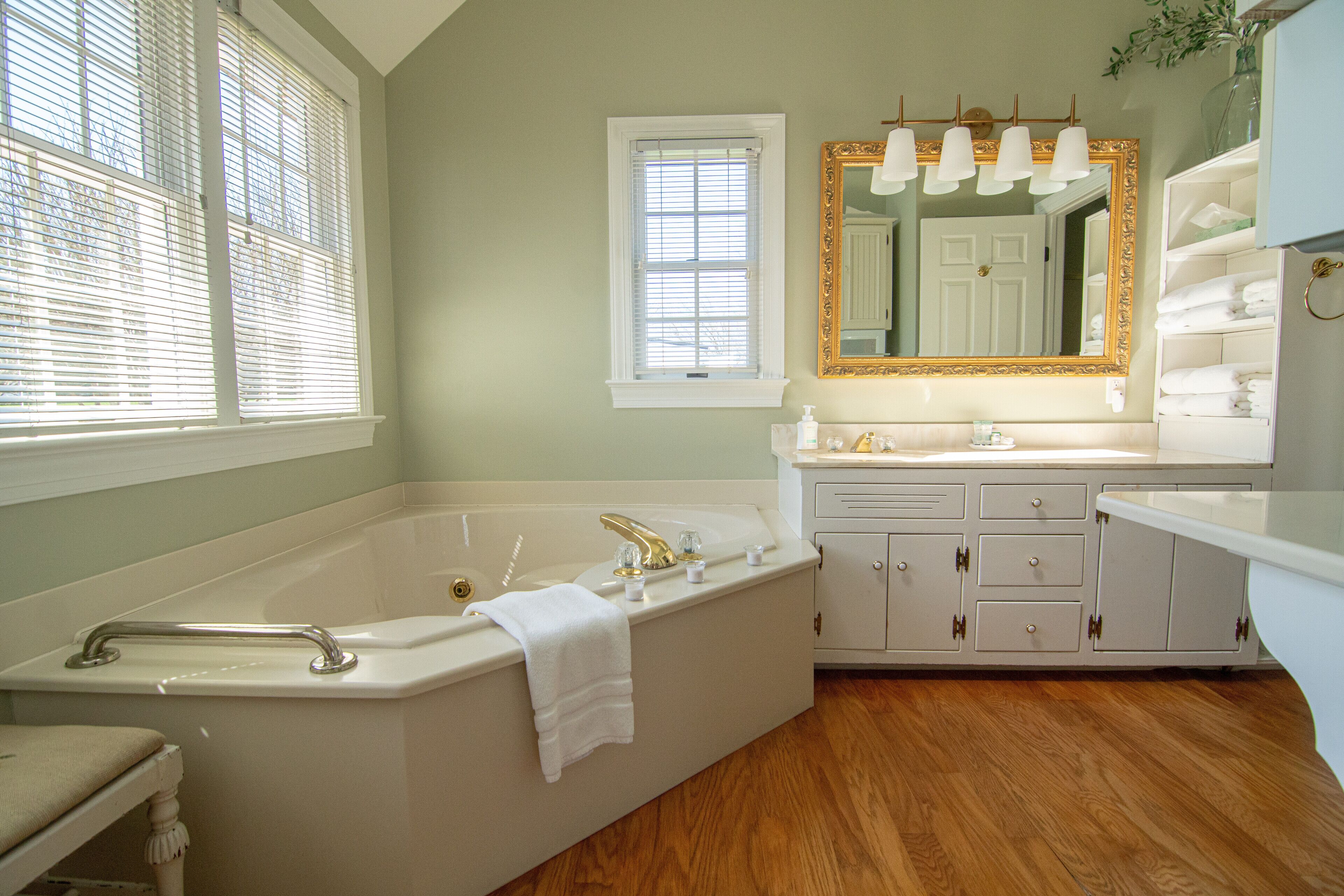 A bathroom with a bathtub, vanity, and a large mirror.