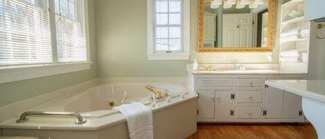 A bathroom with a bathtub, vanity, and a large mirror.