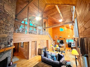 Una cabaña espaciosa con habitación tipo loft, comedor y sala de estar con chimenea.