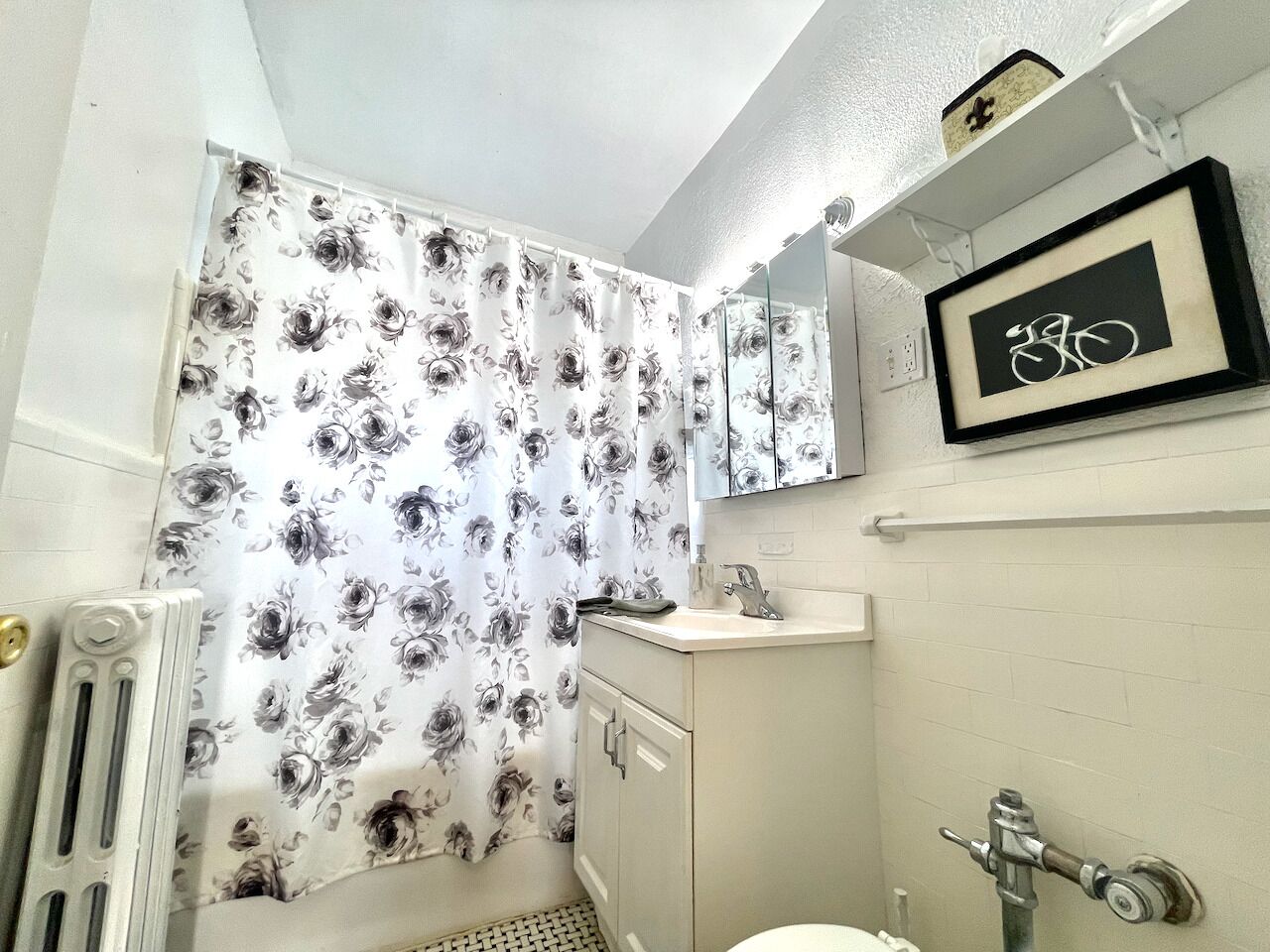 Une salle de bain avec un rideau de douche, un lavabo, un miroir et des toilettes.