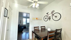 A dining area with a wooden table and chairs, a ceiling fan, and a bicycle mounted on the wall. - 6653 2S | Jewel of Central St. Louis (St. Louis)