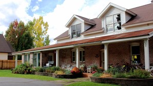 A two-story house with a brick exterior, a covered porch, and a front yard with plants and a stone pathway.