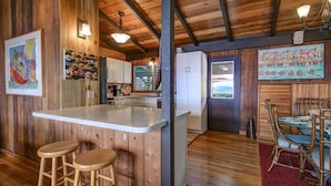 A rustic kitchen with wooden walls, a white countertop, and wooden stools.