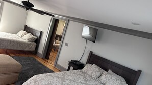 Une chambre avec deux lits, une télévision et un ventilateur de plafond.