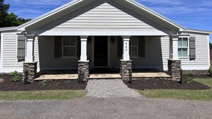 Une maison de plain-pied avec un toit à pignon, un porche à l’avant doté de piliers en pierre et le numéro « 450 » inscrit sur le pilier avant.