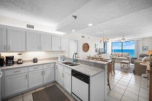 A modern kitchen with white cabinets, a dishwasher, and a large island with a sink.