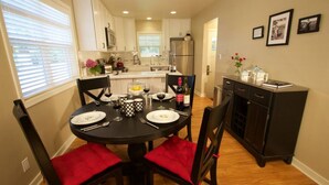 A dining area with a round table, black chairs with red cushions, and a kitchen in the background. - Syvila’s Cottage | Private Garden Near Downtown (Walla Walla)