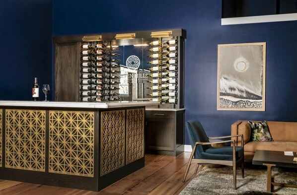 Un coin bar avec un présentoir à bouteilles de vin, un canapé et un tableau accroché au mur.