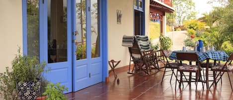 A patio with a table set for dining, a rocking chair, and potted plants.