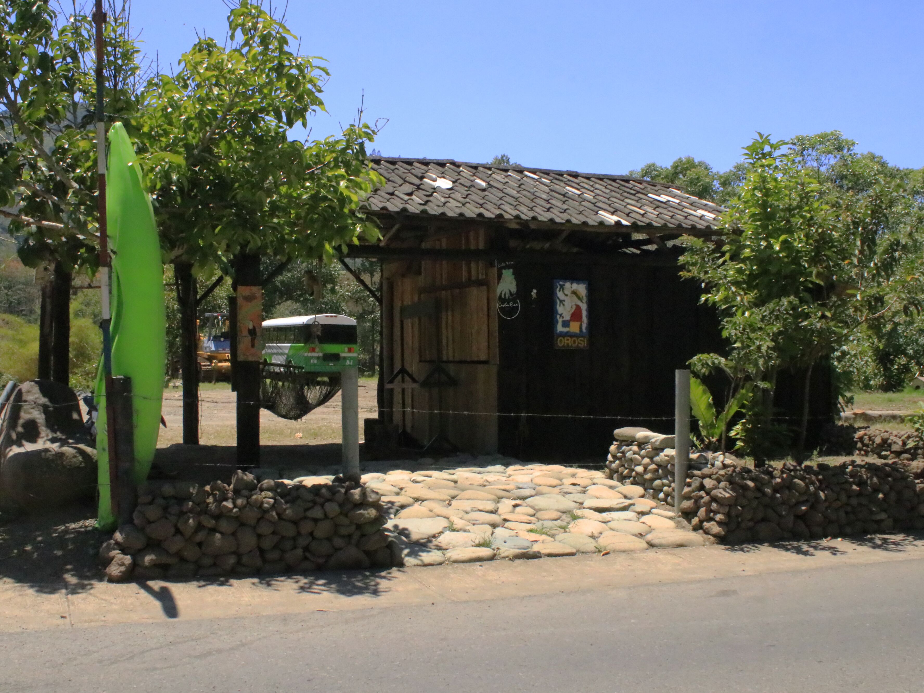 A rustic building with a tiled roof, a wooden door, and a signboard.