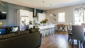 A modern kitchen with white cabinets, a central island, and pendant lighting. - Luxury Home in 12South, Downtown, Gulch, Music Row, Vandy / Roof Tops (Nashville)