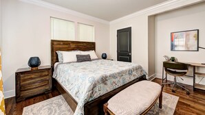 Una camera da letto con un letto di legno, comodini, una scrivania e una sedia.