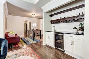 Una cocina moderna con armarios blancos, encimera negra y repisa de madera sobre el fregadero.