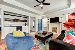 A living room with a fireplace, a television, and a ceiling fan.