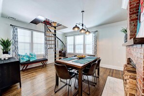A dining area with a wooden table, chairs, a bench, and a spiral staircase.