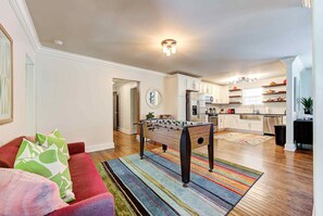 A living room with a foosball table, a red sofa, and a colorful striped rug.