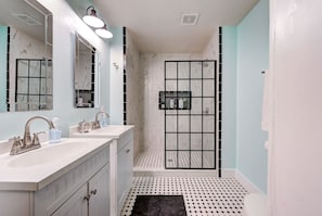 A bathroom with two sinks, a mirror, a shower with a glass door, and a patterned floor.