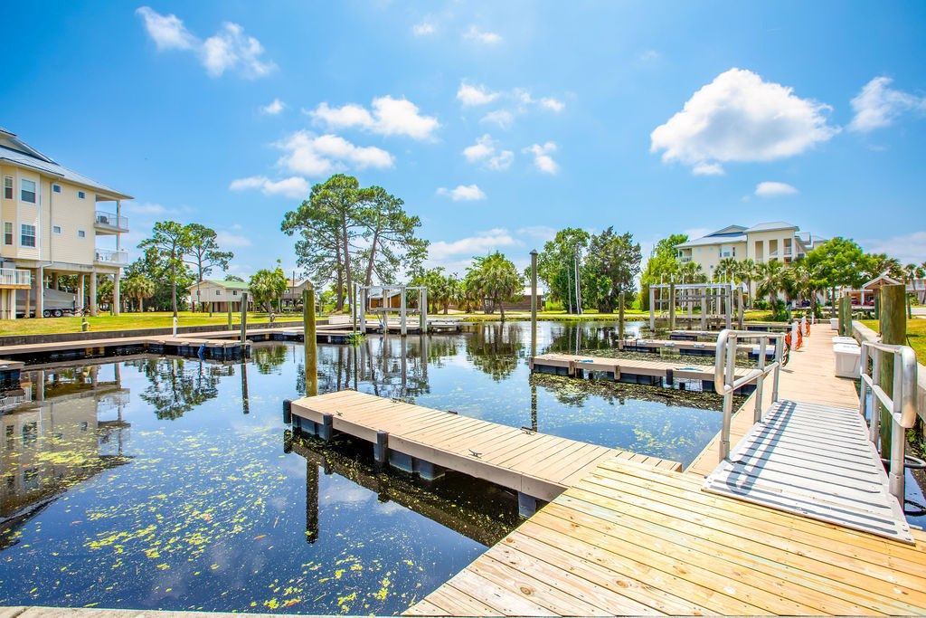 A waterfront property with a dock, calm water, and buildings in the background.