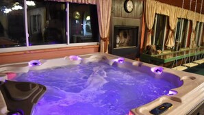 Un jacuzzi con iluminación morada, un reloj y una chimenea al fondo.