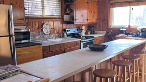 Une cuisine dotée de meubles en bois, d’un réfrigérateur, d’un four à micro-ondes, d’une cuisinière et d’un grand îlot central avec des tabourets de bar.