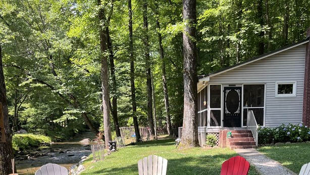 Un espace extérieur accueillant, aménagé avec des fauteuils Adirondack et un foyer, entouré d’un chemin de gravier et d’une végétation luxuriante.