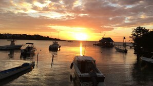 Uma marina com barcos atracados, um píer e um pôr do sol ao fundo.