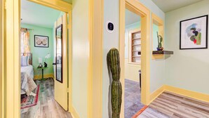 Een hal met een cactus, een spiegel, een schilderij van een vlinder en een lijstwerk aan de muur.
