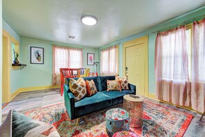 A living room with a sofa, ottoman, and a patterned rug.