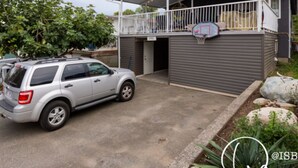 Un immeuble résidentiel doté d’un porche abrité, d’un panier de basketball et d’un VUS garé.