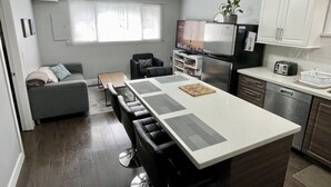Une cuisine moderne dotée d’un îlot central, d’appareils électroménagers intégrés et d’un coin repas comprenant un canapé et des chaises.