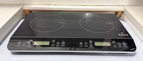A black induction cooktop with two burners, a digital display, and control buttons.