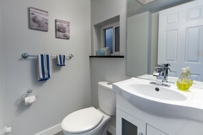 Ein Badezimmer mit Toilette, Waschbecken, Spiegel und zwei Handtüchern an einem Handtuchhalter.