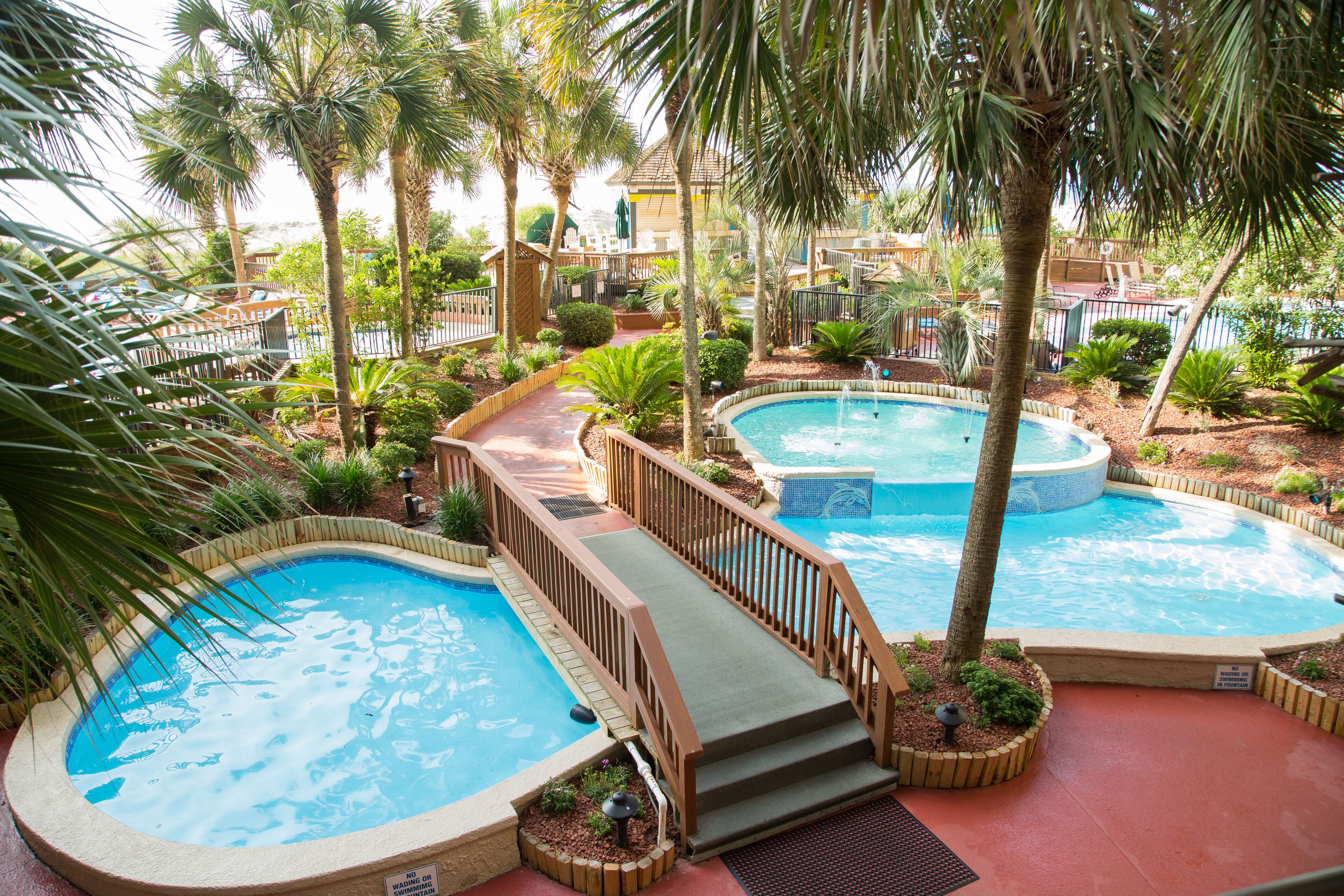 A pool area with multiple hot tubs and a wooden deck.